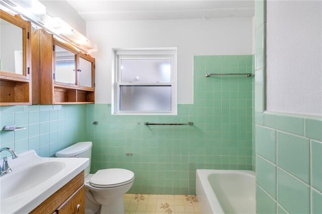 3410 Plymouth Pl, New Orleans, LA 70131 - full bathroom with tile walls, a tub, toilet, vanity, and wainscoting