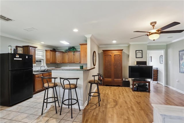 4811 Perelli Dr, New Orleans, LA 70127 - kitchen with freestanding refrigerator, a breakfast bar area, crown molding, ceiling fan, and baseboards