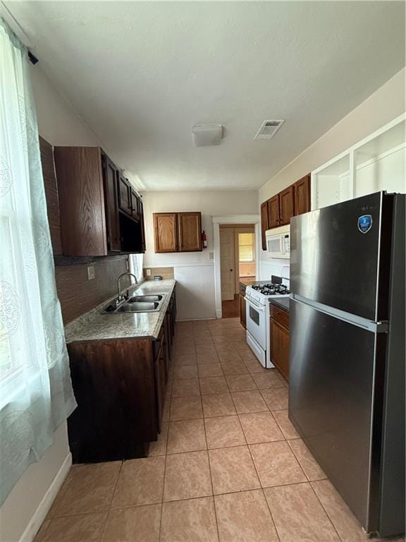 4218 S Liberty St, New Orleans, LA 70115 - kitchen with white appliances, a sink, and light tile patterned floors