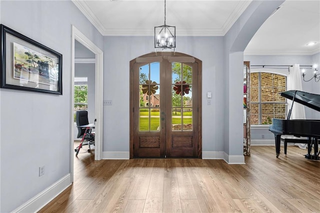 1180 Brook Ct, Mandeville, LA 70448 - foyer featuring arched walkways, a chandelier, french doors, light wood-type flooring, and crown molding