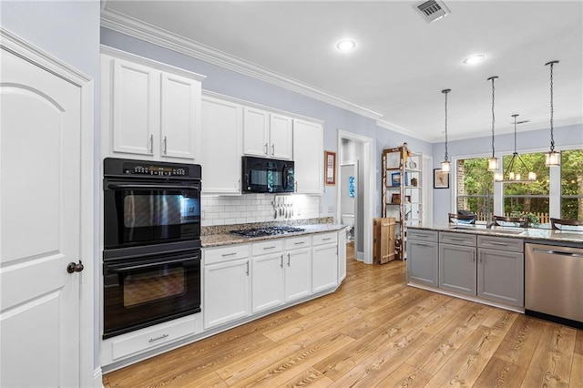 1180 Brook Ct, Mandeville, LA 70448 - kitchen featuring black appliances, light wood-style floors, backsplash, decorative light fixtures, and light stone countertops