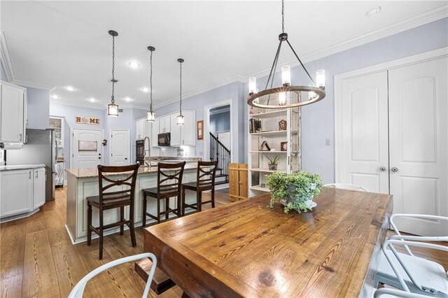 1180 Brook Ct, Mandeville, LA 70448 - dining area with hardwood / wood-style floors, crown molding, recessed lighting, and a chandelier