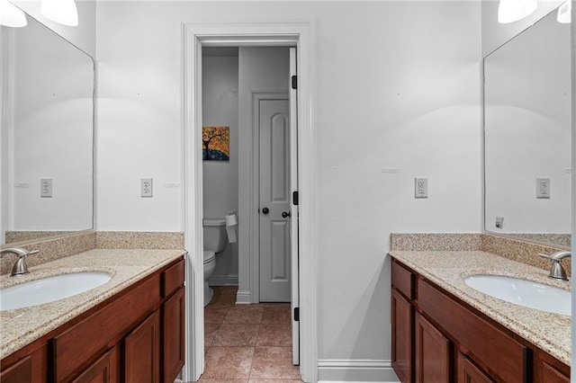 1180 Brook Ct, Mandeville, LA 70448 - bathroom with toilet, two vanities, tile patterned floors, and baseboards