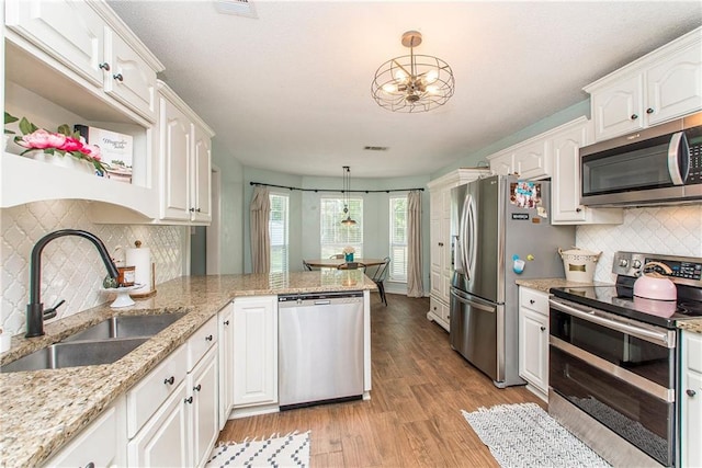 47380 Cardinal Dr, Franklinton, LA 70438 - kitchen with stainless steel appliances, white cabinets, tasteful backsplash, a peninsula, and light wood-style flooring