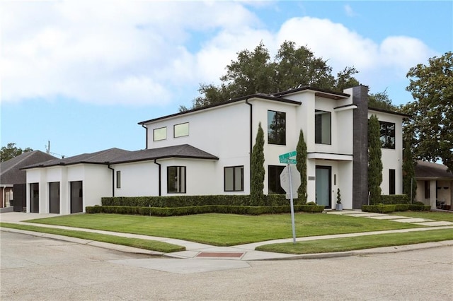 1900 Giuffrias Ave, Metairie, LA 70001 - contemporary home with an attached garage, concrete driveway, stucco siding, a chimney, and a front yard