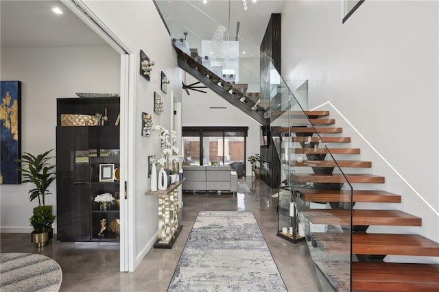 1900 Giuffrias Ave, Metairie, LA 70001 - entrance foyer featuring concrete floors, stairway, a high ceiling, and baseboards