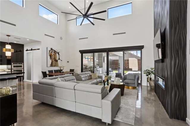 1900 Giuffrias Ave, Metairie, LA 70001 - living area featuring a barn door, healthy amount of natural light, a towering ceiling, finished concrete flooring, and recessed lighting