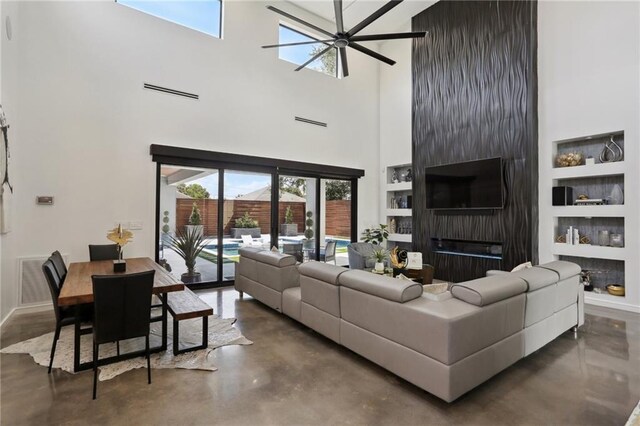 1900 Giuffrias Ave, Metairie, LA 70001 - living area with finished concrete flooring, built in features, a towering ceiling, baseboards, and ceiling fan