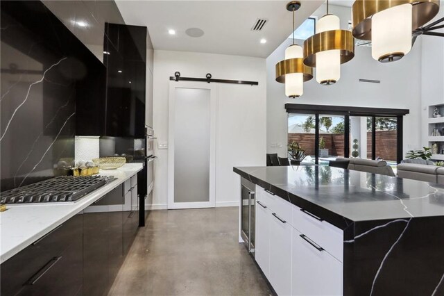 1900 Giuffrias Ave, Metairie, LA 70001 - kitchen featuring modern cabinets, a barn door, concrete floors, open floor plan, and a towering ceiling