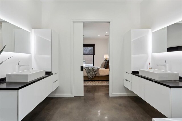 1900 Giuffrias Ave, Metairie, LA 70001 - bathroom featuring concrete floors, connected bathroom, two vanities, baseboards, and recessed lighting