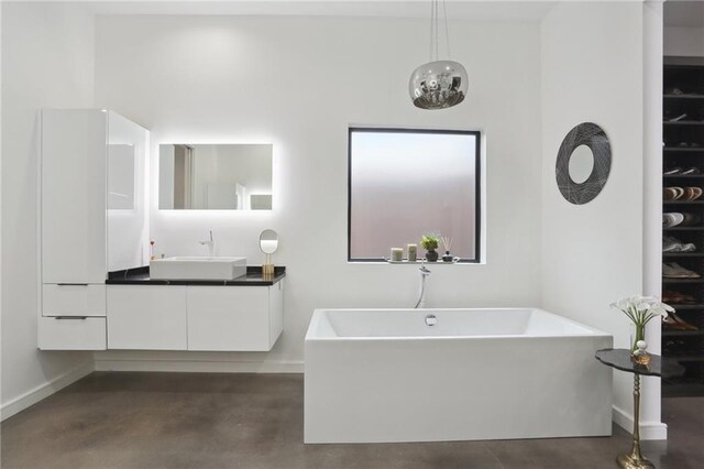 1900 Giuffrias Ave, Metairie, LA 70001 - full bath featuring vanity, a freestanding tub, baseboards, and finished concrete floors