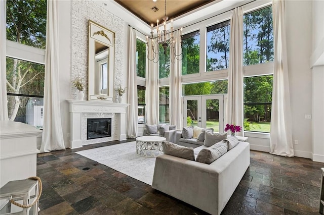 4 N Azalea Dr, Covington, LA 70433 - living room with a high ceiling, stone tile flooring, french doors, a chandelier, and a fireplace