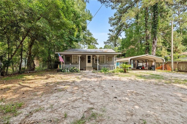 72272 Gurtner Dr, Abita Springs, LA 70420 - view of front of house with a porch, dirt driveway, a detached carport, and metal roof