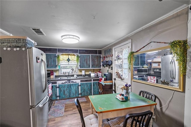 72272 Gurtner Dr, Abita Springs, LA 70420 - kitchen with stainless steel appliances, a sink, wood finished floors, ornamental molding, and dark countertops