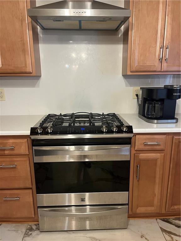 1912 Bullard Ave, Metairie, LA 70003 - kitchen with stainless steel gas range, wall chimney exhaust hood, light marble finish flooring, light countertops, and brown cabinetry