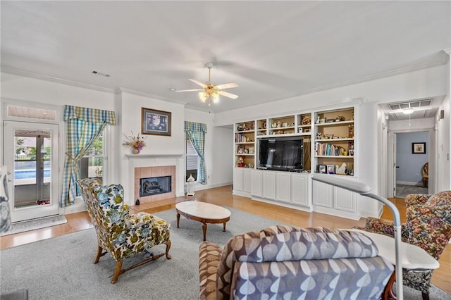 18332 Honeysuckle Dr, Ponchatoula, LA 70454 - living room with attic access, ornamental molding, light wood-style flooring, a ceiling fan, and a tiled fireplace