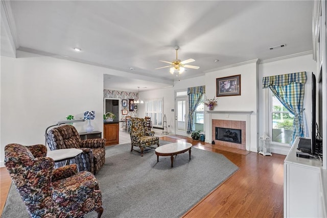 18332 Honeysuckle Dr, Ponchatoula, LA 70454 - living area featuring ornamental molding, plenty of natural light, ceiling fan, light wood-style floors, and a tile fireplace