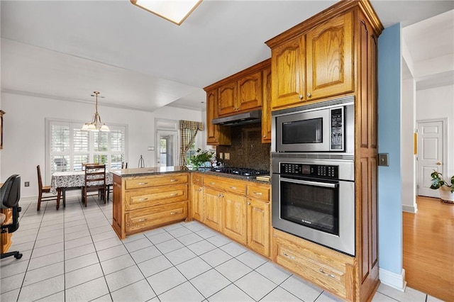 18332 Honeysuckle Dr, Ponchatoula, LA 70454 - kitchen featuring appliances with stainless steel finishes, under cabinet range hood, a peninsula, baseboards, and dark countertops