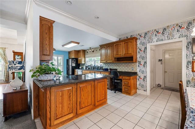 18332 Honeysuckle Dr, Ponchatoula, LA 70454 - kitchen with ornamental molding, brown cabinetry, freestanding refrigerator, light tile patterned floors, and dark stone counters