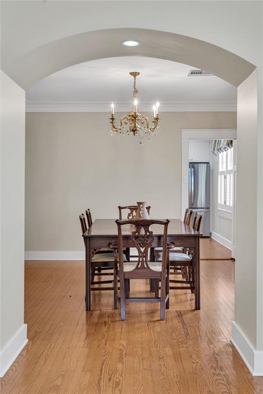 324 Fairway Dr, New Orleans, LA 70124 - dining room with arched walkways, ornamental molding, a chandelier, light wood-style flooring, and baseboards
