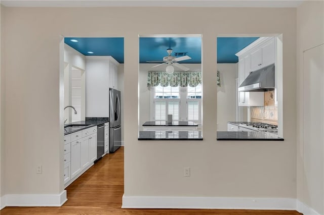 324 Fairway Dr, New Orleans, LA 70124 - kitchen with a sink, under cabinet range hood, stainless steel appliances, a ceiling fan, and dark countertops