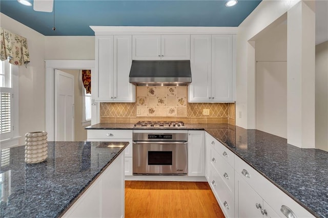324 Fairway Dr, New Orleans, LA 70124 - kitchen featuring appliances with stainless steel finishes, under cabinet range hood, white cabinets, tasteful backsplash, and dark stone countertops