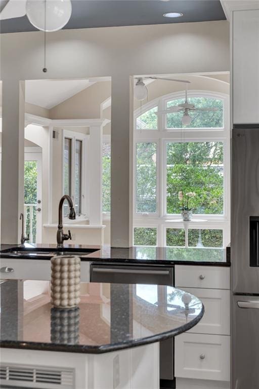 324 Fairway Dr, New Orleans, LA 70124 - kitchen featuring appliances with stainless steel finishes, white cabinetry, dark stone counters, a sink, and vaulted ceiling