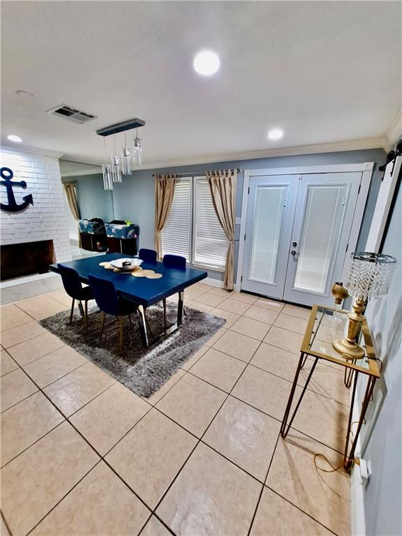 120 Whisperwood Blvd, Slidell, LA 70458 - dining space with a brick fireplace, light tile patterned floors, french doors, recessed lighting, and ornamental molding