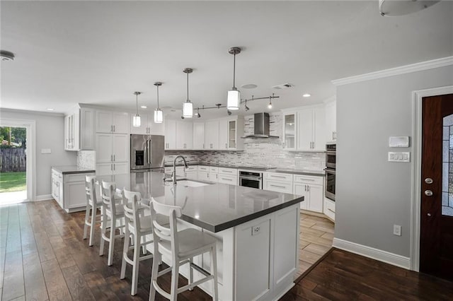 9509 Robin Ln, River Ridge, LA 70123 - kitchen featuring appliances with stainless steel finishes, a sink, wall chimney range hood, baseboards, and ornamental molding