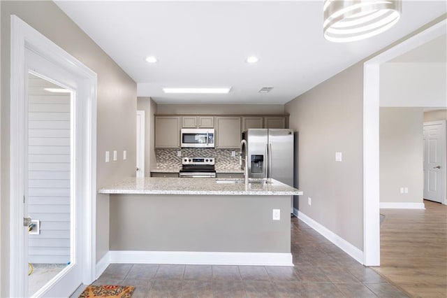 70382 10th St, Covington, LA 70433 - kitchen featuring stainless steel appliances, gray cabinetry, baseboards, backsplash, and a sink