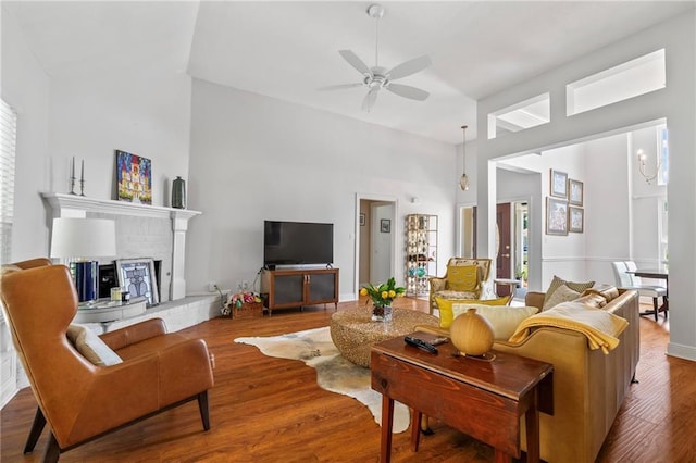 1833 Octavia Dr, Mandeville, LA 70448 - living room featuring a high ceiling, a ceiling fan, wood finished floors, a brick fireplace, and plenty of natural light