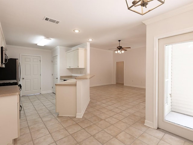 653 Beaulieux St, Mandeville, LA 70448 - kitchen featuring freestanding refrigerator, light countertops, stainless steel microwave, ceiling fan, and white cabinetry