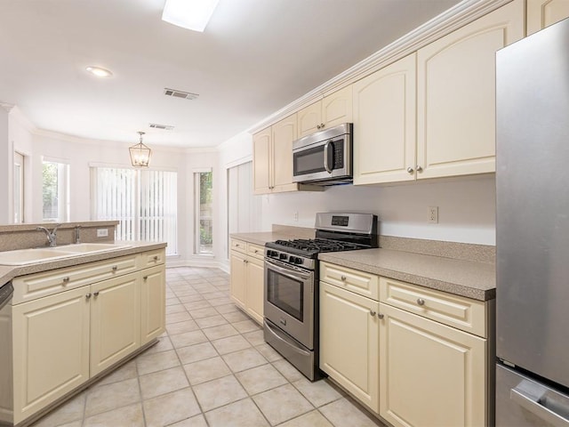 653 Beaulieux St, Mandeville, LA 70448 - kitchen featuring appliances with stainless steel finishes, cream cabinetry, a sink, ornamental molding, and light tile patterned flooring