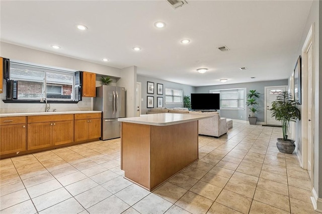 4616 Kawanee Ave, Metairie, LA 70006 - kitchen featuring freestanding refrigerator, light countertops, brown cabinetry, a center island, and recessed lighting