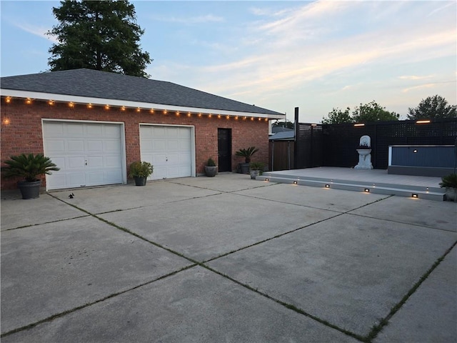 4616 Kawanee Ave, Metairie, LA 70006 - property exterior at dusk with brick siding, a garage, concrete driveway, and a shingled roof