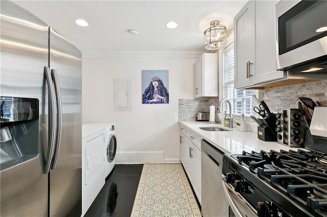 1030 Kerlerec St Unit 4, New Orleans, LA 70116 - kitchen with stainless steel appliances, washer and clothes dryer, a sink, decorative backsplash, and ornamental molding