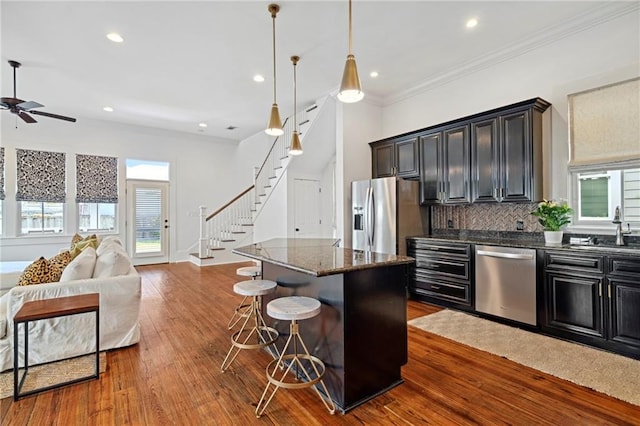 1215 Saint Andrew St, New Orleans, LA 70130 - kitchen with stainless steel appliances, open floor plan, backsplash, a kitchen island, and a ceiling fan