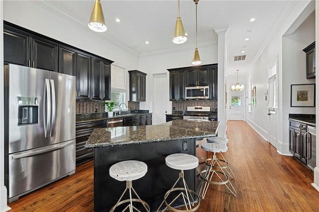 1215 Saint Andrew St, New Orleans, LA 70130 - kitchen featuring appliances with stainless steel finishes, a center island, tasteful backsplash, a kitchen bar, and dark stone counters