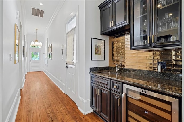 1215 Saint Andrew St, New Orleans, LA 70130 - indoor wet bar with beverage cooler, decorative backsplash, crown molding, wood finished floors, and baseboards