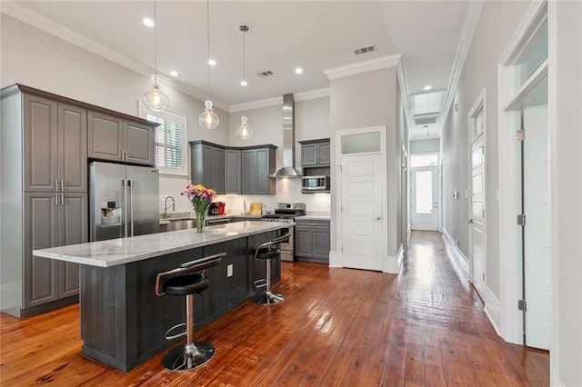 4823 Dreux Ave, New Orleans, LA 70126 - kitchen with appliances with stainless steel finishes, gray cabinets, wall chimney exhaust hood, a breakfast bar area, and a kitchen island
