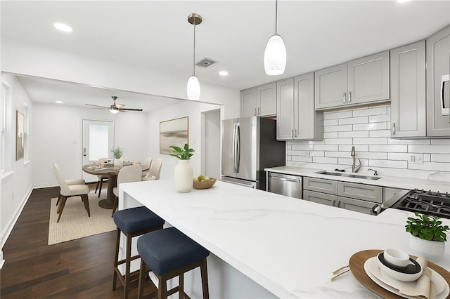 903 N Turnbull Dr, Metairie, LA 70001 - kitchen featuring stainless steel appliances, gray cabinetry, dark wood-style flooring, backsplash, and light stone countertops