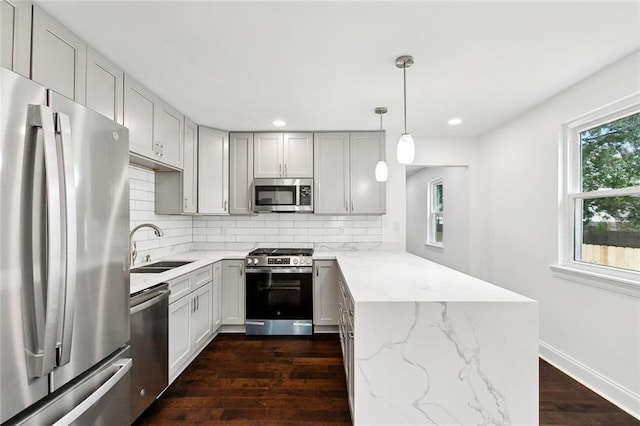 903 N Turnbull Dr, Metairie, LA 70001 - kitchen featuring stainless steel appliances, a peninsula, dark wood-style flooring, decorative backsplash, and light stone counters