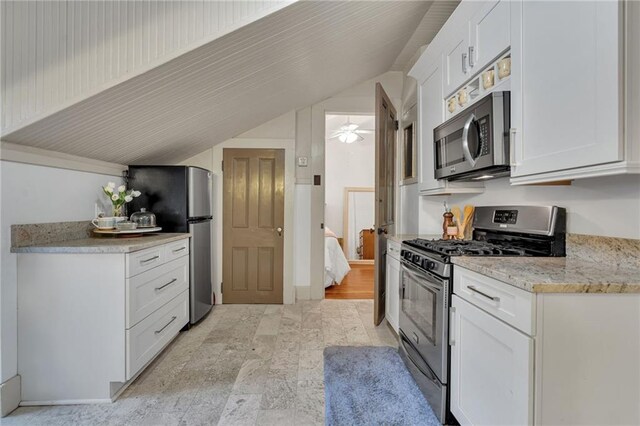 515 Saint Louis St Unit 6, New Orleans, LA 70130 - kitchen featuring appliances with stainless steel finishes, vaulted ceiling, white cabinetry, light stone finish flooring, and light stone counters