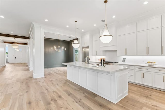1617 Homer St, Metairie, LA 70005 - kitchen with a chandelier, a sink, an island with sink, white cabinetry, and ornamental molding