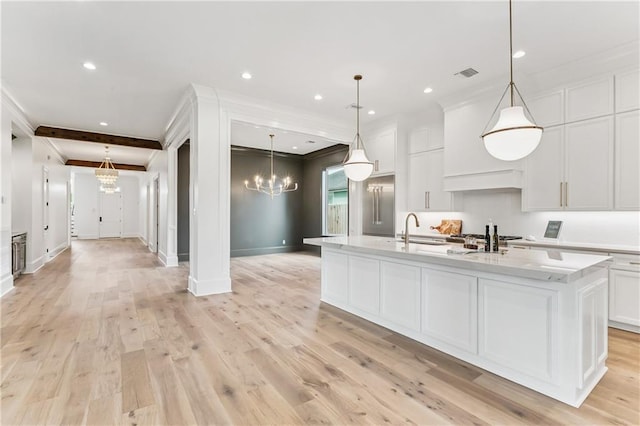 1617 Homer St, Metairie, LA 70005 - kitchen featuring crown molding, a chandelier, white cabinets, a center island with sink, and light wood finished floors