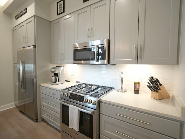 731 St Charles Ave Unit 305, New Orleans, LA 70130 - kitchen with appliances with stainless steel finishes, gray cabinetry, backsplash, and light wood-type flooring