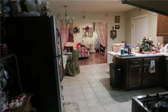 221513 James St, Jefferson, LA 70121 - kitchen with a chandelier, freestanding refrigerator, light tile patterned flooring, a peninsula, and light countertops