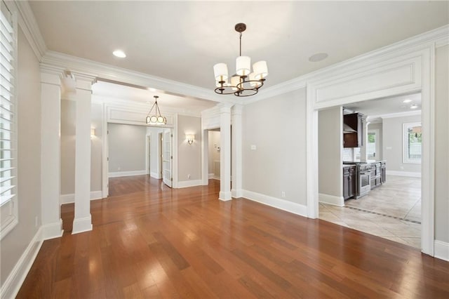 404 Atherton Dr, Metairie, LA 70005 - unfurnished dining area featuring ornamental molding, a chandelier, light wood finished floors, baseboards, and ornate columns