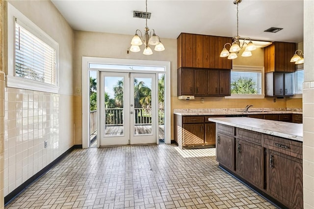 400 Aris Ave, Metairie, LA 70005 - kitchen with a chandelier, light countertops, a sink, and brick patterned floors