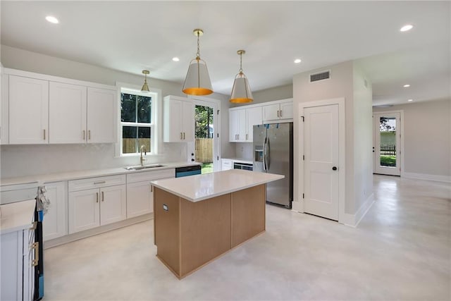 218 N Jackson Ave, Covington, LA 70433 - kitchen with stainless steel appliances, a sink, a kitchen island, light countertops, and white cabinetry